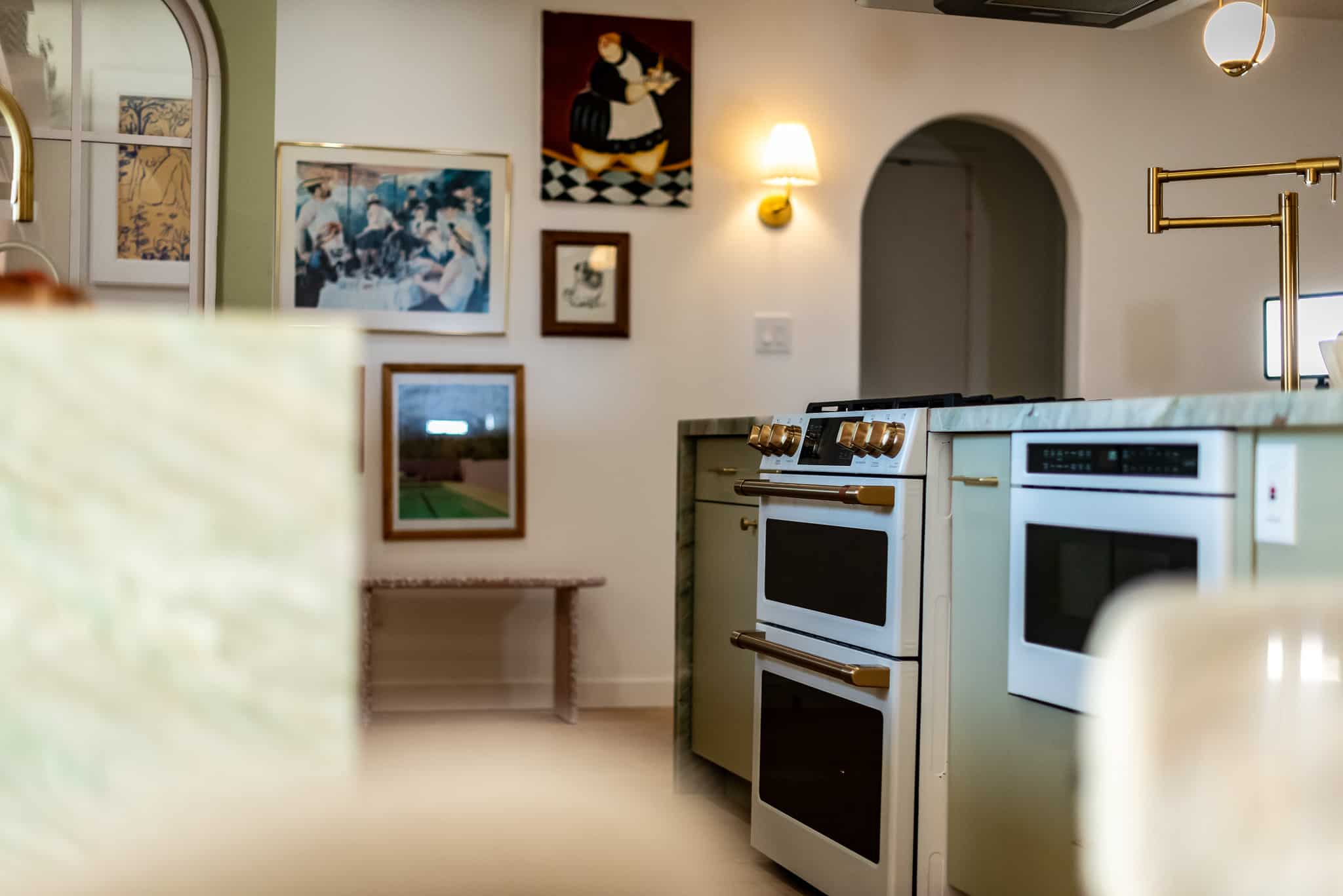 A cafe stove in a kitchen island after a remodel that was completed. other features in the photo include microwave drawer, pot filler, and decorative paintings